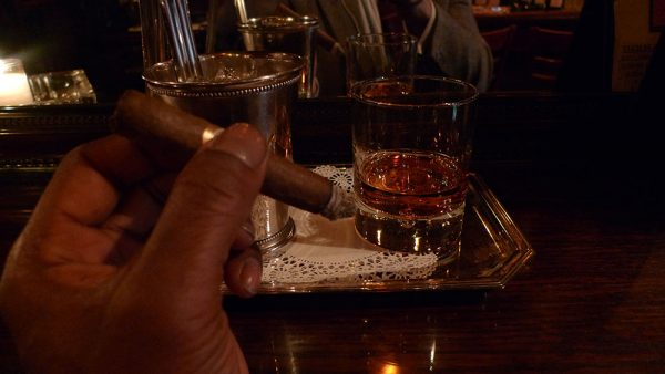Glass of bourbon with cigar in hand
